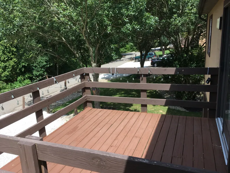 Wooden townhome balcony overlooking the tree-lined drive
