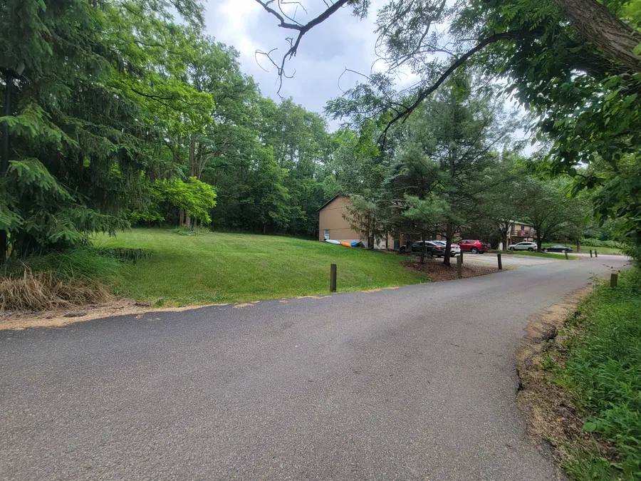 Curving drive bordered by green lawns, mature trees and Hidden Pines townhomes