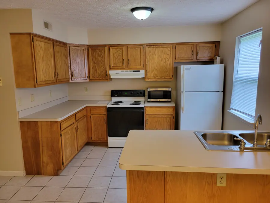 Premier kitchen with wood cabinets, refrigerator, stove and sink peninsula