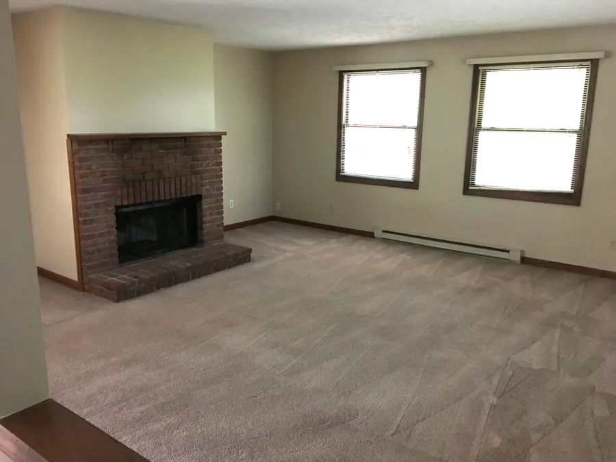 Premier interior with carpet, two windows and a brick fireplace surround