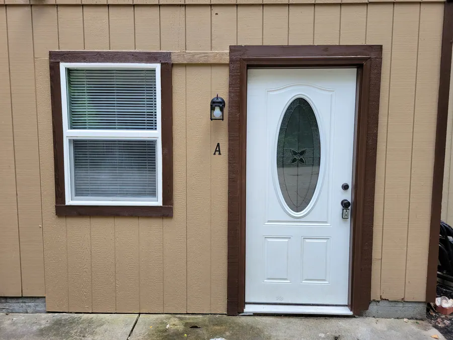 Studio exterior entrance beside a window in brown siding